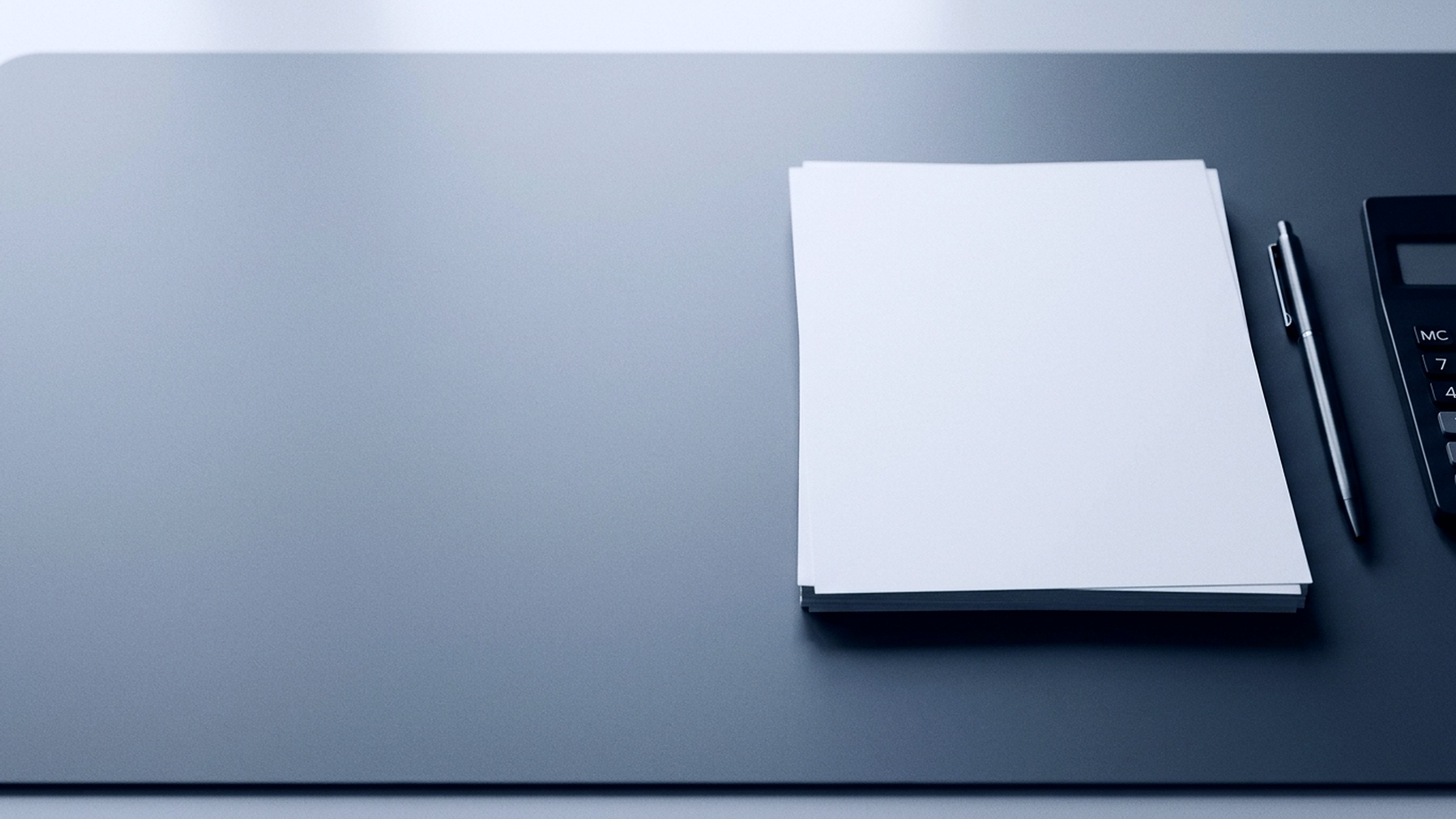Printed financial statements stacked and squared up on a desk in cool daylight.