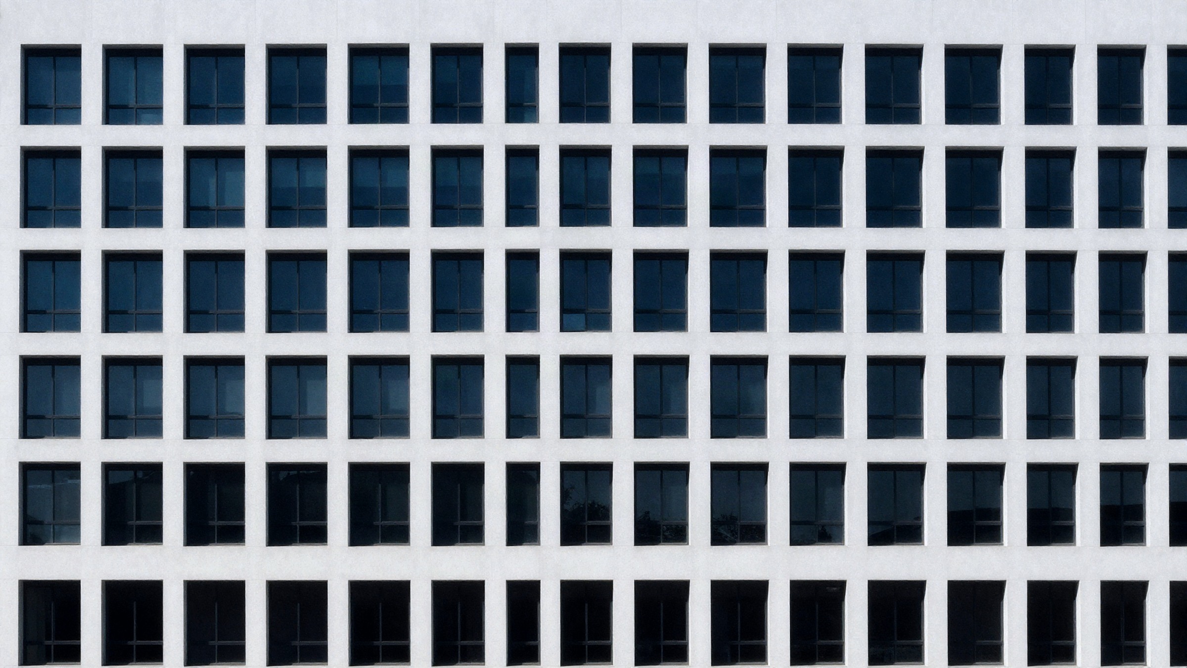 A modern façade of identical windows shot square-on, forming a repeating grid.